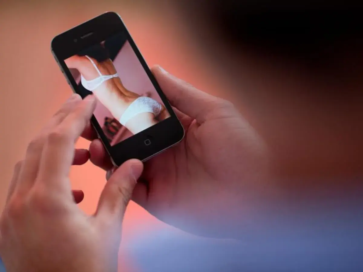 Hände halten ein Smartphone, das ein Bild einer Frau in Unterwäsche zeigt. Ein Moment der Versuchung, der die Kraft des "no fap" unterstreicht.