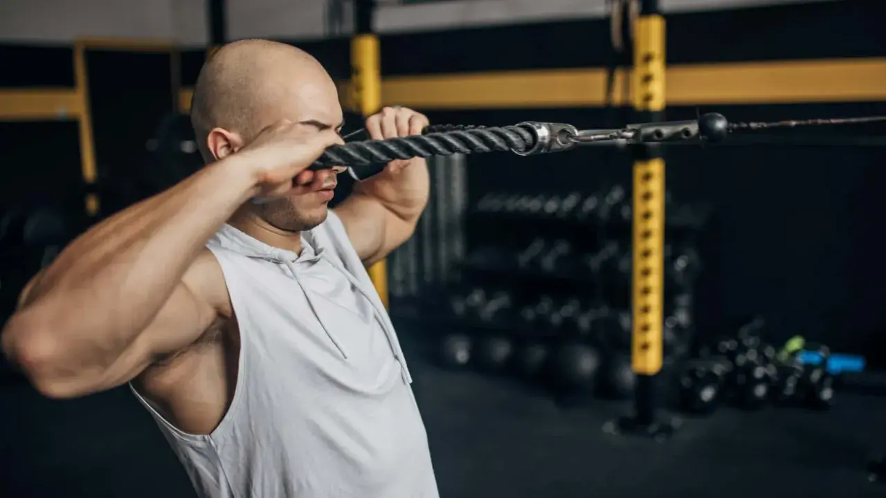 Mann macht Face Pulls am Kabelzug im Fitnessstudio.