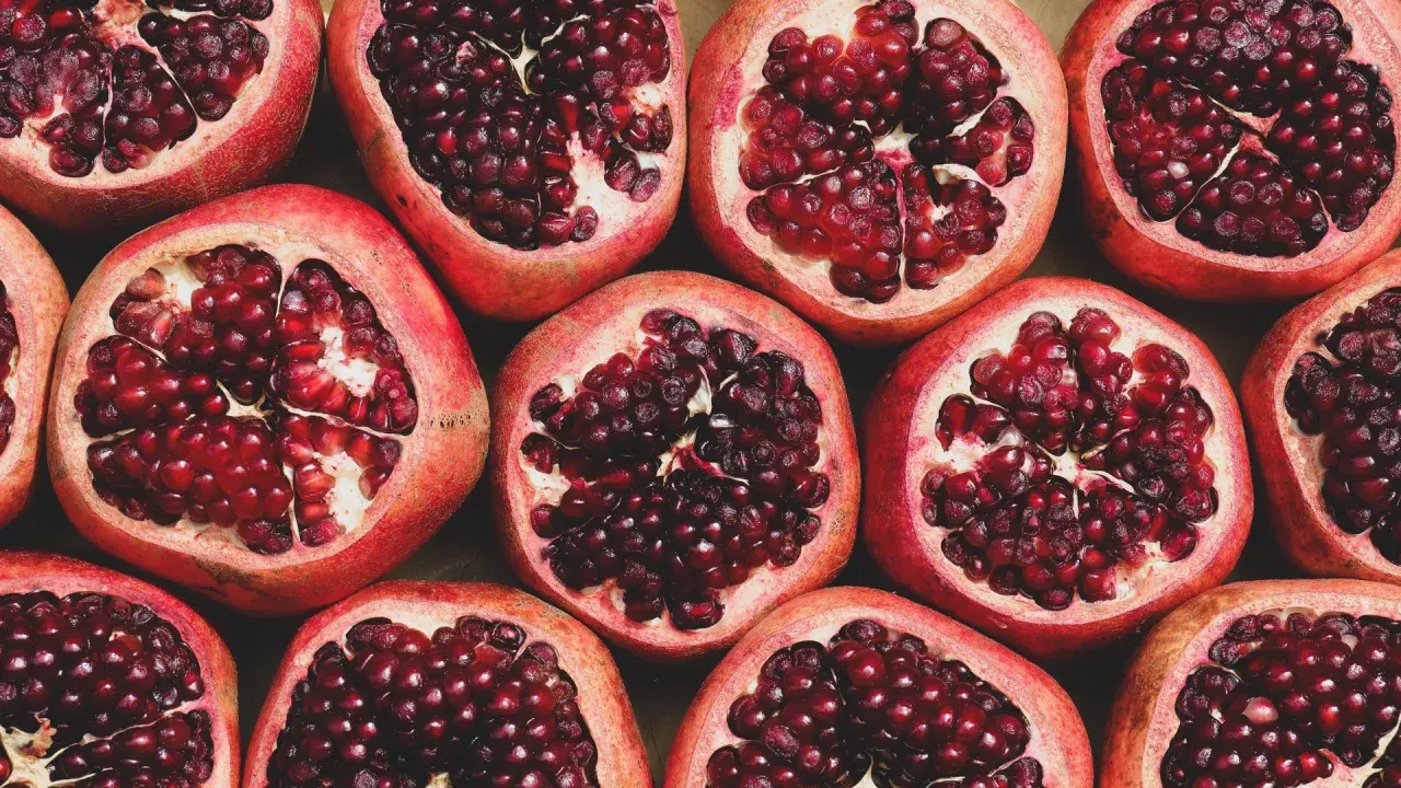 Viele aufgeschnittene Granatäpfel mit leuchtend roten Kernen. Ein wahrhaft **granatapfel gesund** Genuss für Körper und Seele.