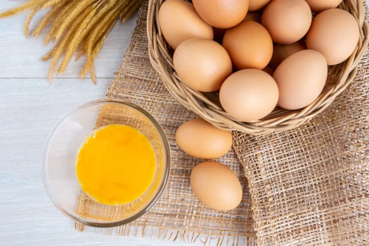 Eier in einem Korb und ein Glas Eigelb. Eine **Eier Vitamine Tabelle** könnte diese Nährstoffe detailliert auflisten.