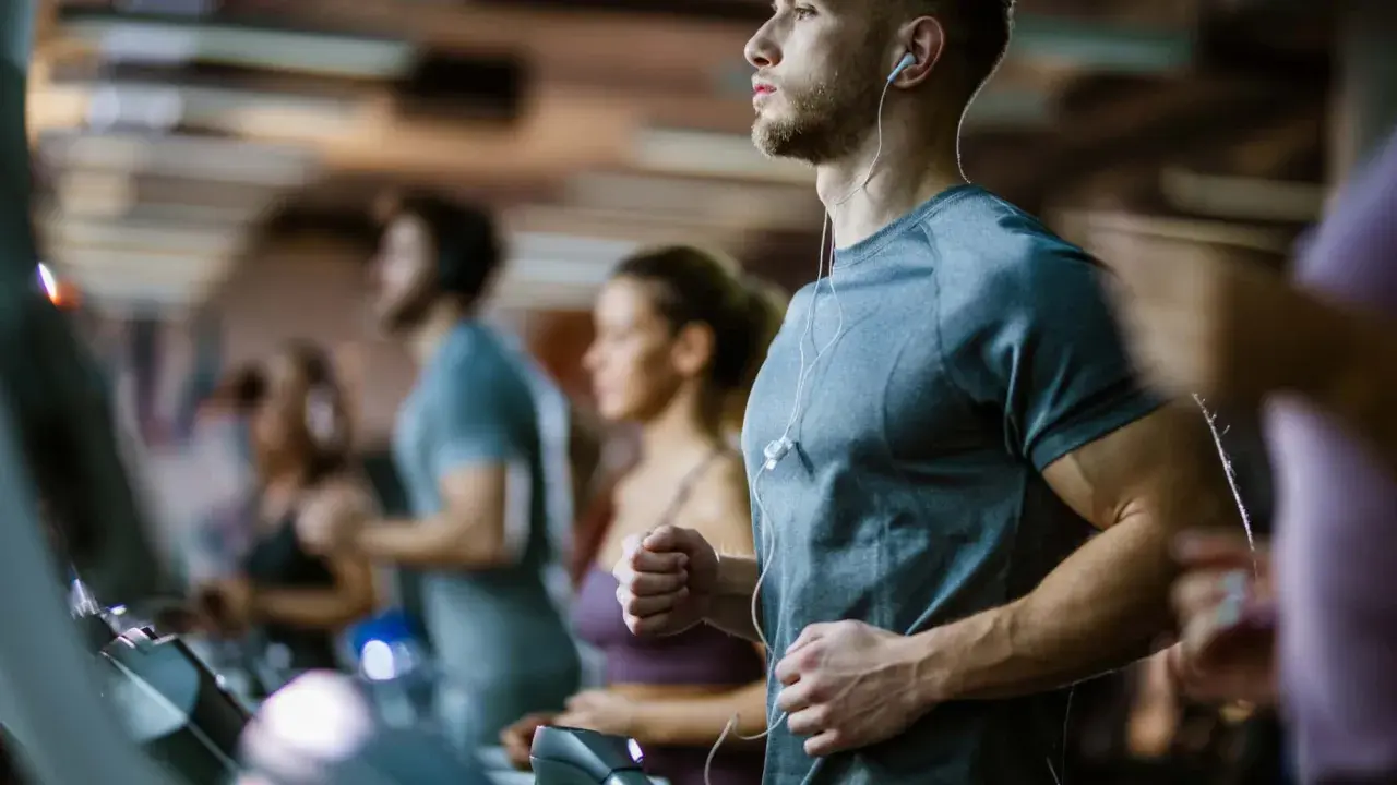 Sportler auf Laufbändern im Fitnessstudio, die auf ihren anaeroben Training Puls achten.