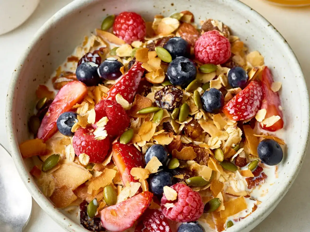 Gesundes Müsli mit Beeren, Nüssen und Kokoschips. Sind Sojaflocken gesund? Ja, sie sind eine gute Proteinquelle.