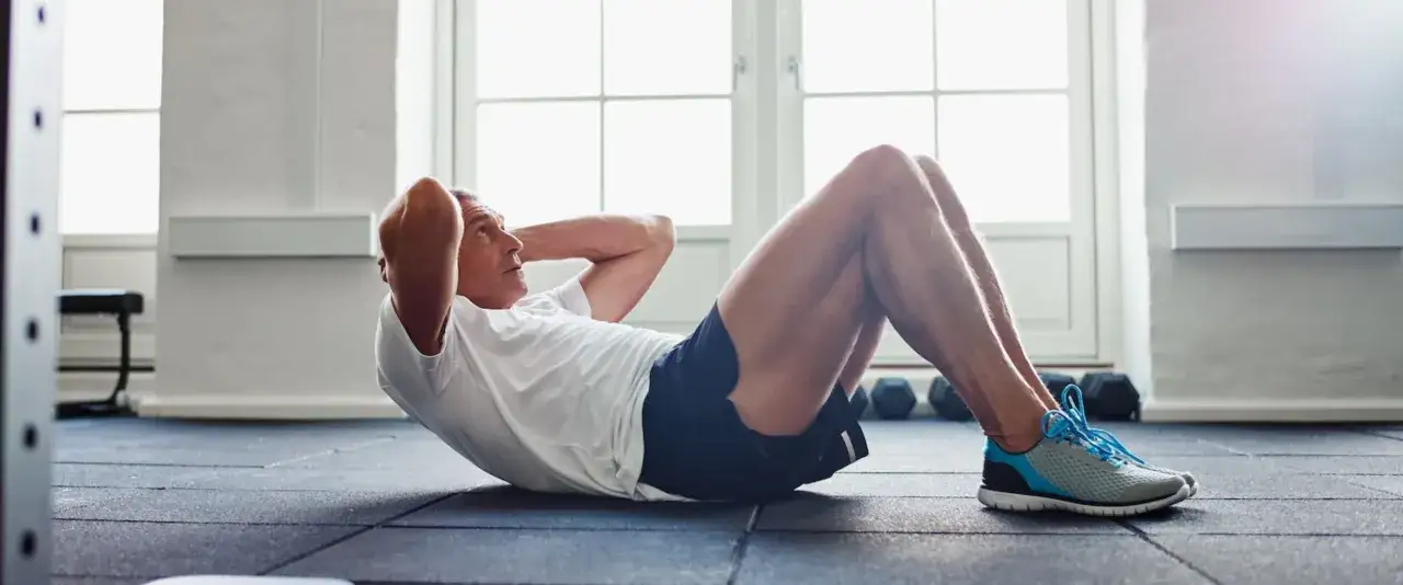 Mann macht Crunches im Fitnessstudio. So bekommt man ein Sixpack: Regelmäßiges Bauchmuskeltraining ist der Schlüssel.