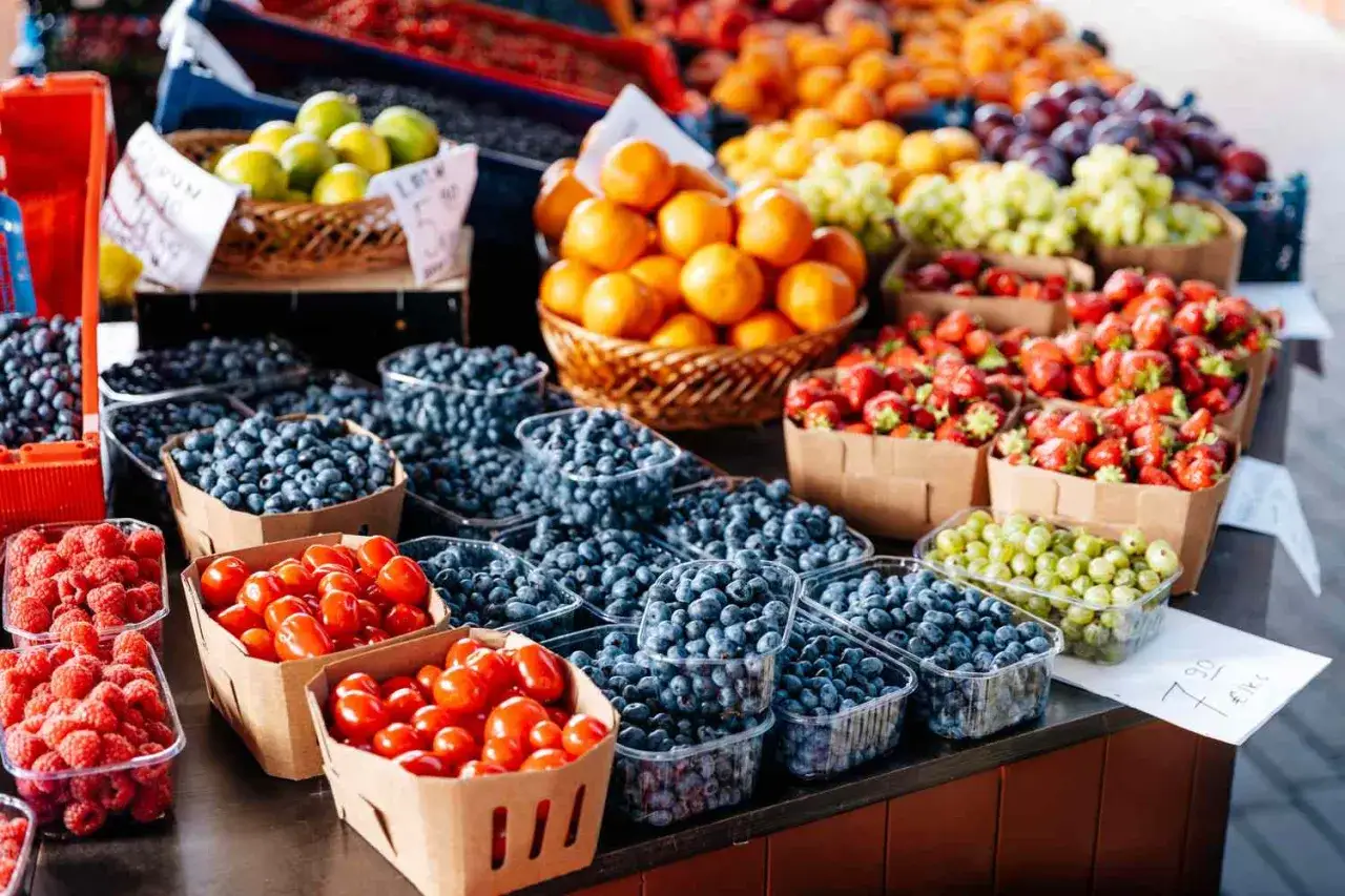 Frischer Beeren- und Obststand. Hier gibt es viele gesunde Kohlenhydrate in Form von Blaubeeren, Erdbeeren, Himbeeren, Kirschtomaten und mehr.