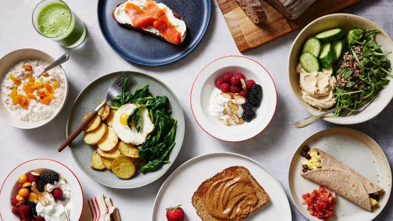 Vielfältige Frühstücksoptionen: Haferflocken mit Trockenfrüchten, Rührei mit Spinat und Kartoffeln, Joghurt mit Beeren, Hummus-Salat, Burrito und Toast mit Nussbutter – alles gute B1 Vitamin Lebensmittel.