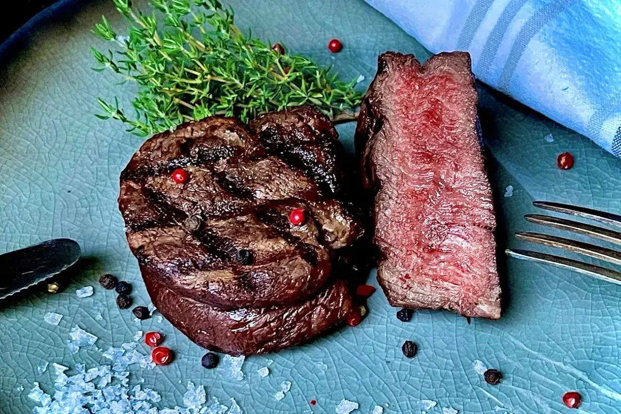 Perfekt gegrilltes Rinderfilet mit zarten rosa Kern, garniert mit Thymian, Pfeffer und grobem Salz. Ein Genuss für Fleischliebhaber.