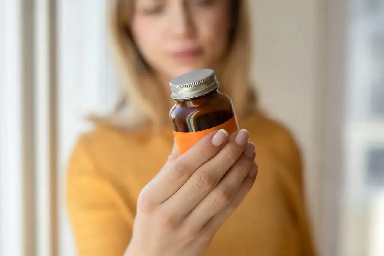 Frau pr&uuml;ft die Dosierung auf einem Fl&auml;schchen. Sie fragt sich, wieviel Q10 am Tag optimal ist.