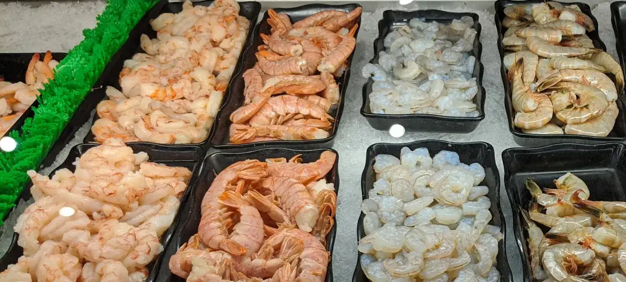 Frische Garnelen in verschiedenen Größen und Sorten, präsentiert auf Eis. Eine Tabelle zum Jodgehalt von Fisch und Meeresfrüchten könnte hier nützlich sein.