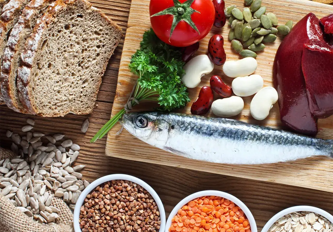 Kupfer-reiche Lebensmittel wie Fisch, Leber und H&uuml;lsenfr&uuml;chte k&ouml;nnen die Psyche positiv beeinflussen. Brot, Tomaten, K&uuml;rbiskerne und Petersilie sind ebenfalls abgebildet.