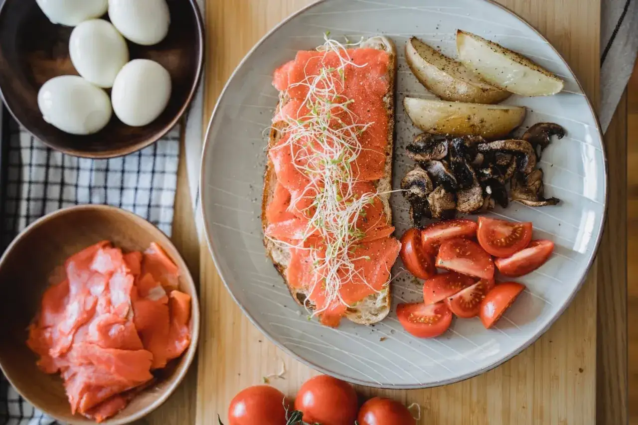 Frühstücksteller mit Lachs-Toast, Kartoffelspalten, Pilzen und Tomaten. Ein gesunder Start, der an Beta-Alanin-Lebensmittel erinnert.