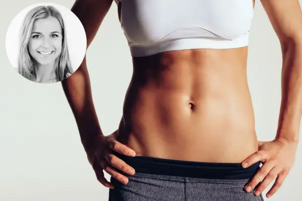 Frau mit straffem Bauch, die zeigt, wie bekommt man ein Sixpack durch Training und gesunde Ernährung.