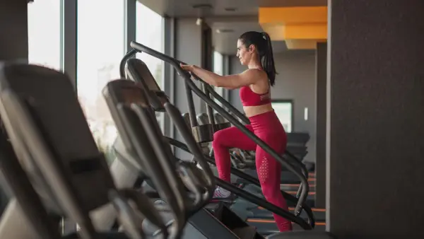 Frau trainiert auf einem Treppensteiger im Fitnessstudio. Was bringt Treppensteigen? Es stärkt Beine und Po, verbessert die Ausdauer und verbrennt Kalorien.